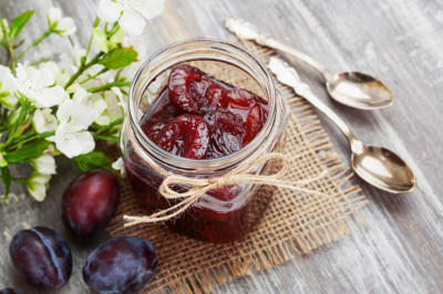 Plum jam in a glass jar on the wooden table