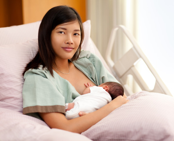 Woman in a hospital bed breastfeeding a child