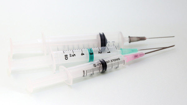 Three disposable medical syringes on a white background.