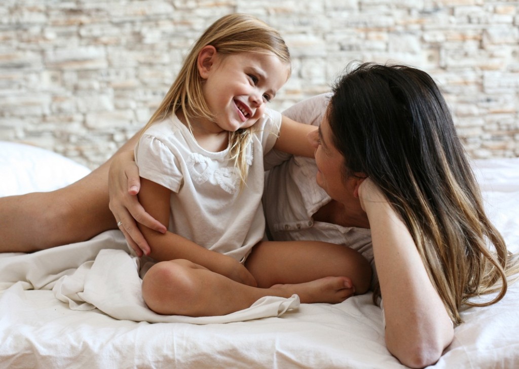 Mother and daughter enjoy in bed.