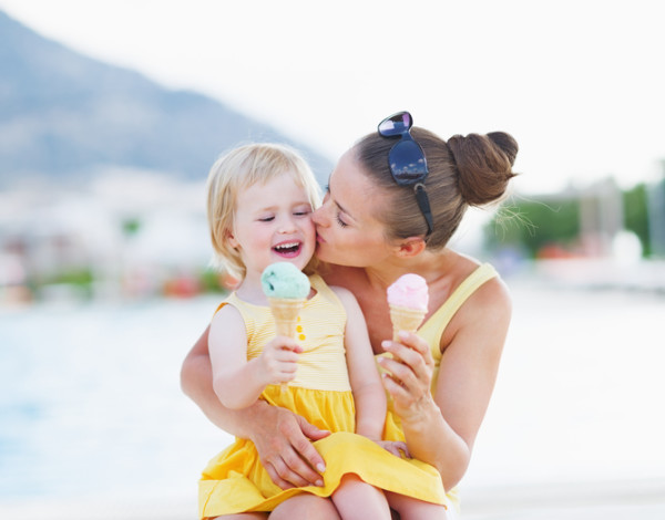 mother kissing baby while eating ice cream